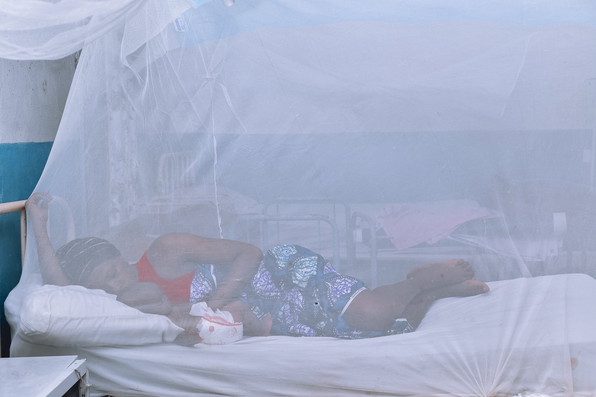 Pregnant woman resting under an insecticide-treated mosquito net at a health facility in Sierra Leone